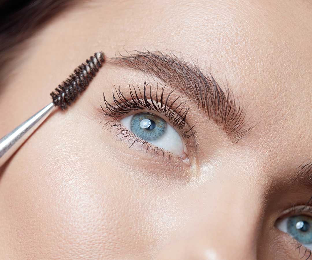 Cosmetic brush placed to the right of woman's eye after eyebrow tattoo.